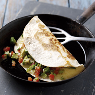 Chopped tomatoes, avocado and spring onions inside of a folded tortilla.